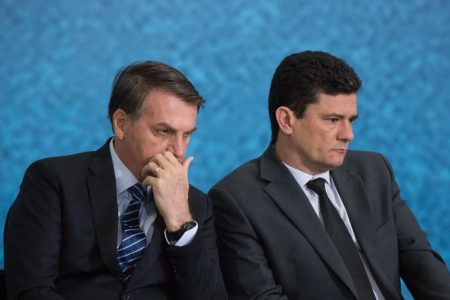 Na imagem colorida, dois homens estão centralizados. Eles usam terno e gravada escuro, possuem cabelo curto e ambos são brancos