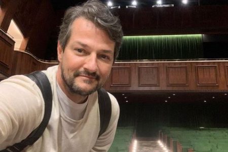 Foto colorida de Marcelo Serrado em frente ao palco de um teatro - Metrópoles
