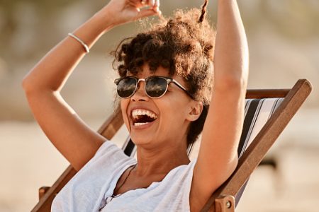 mulher de cabelo crespo sorrindo na praia