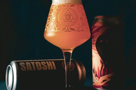 Na foto vemos duas latas de cerveja, uma em pé e outra deitada e uma taça cheia de cerveja