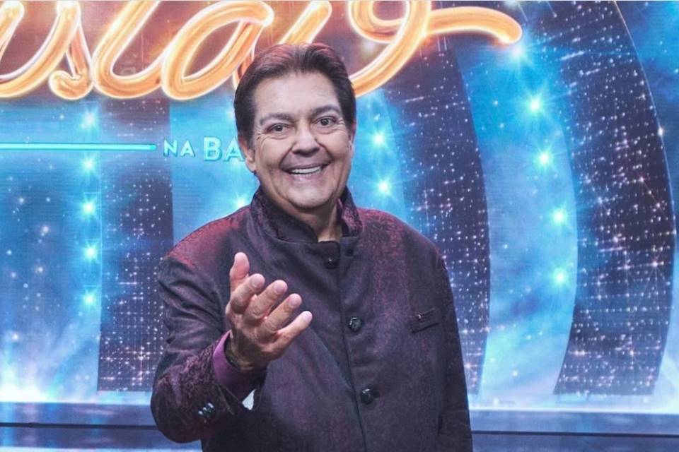 Foto colorida de Faustão de casaco preto em seu programa na Band - Metrópoles