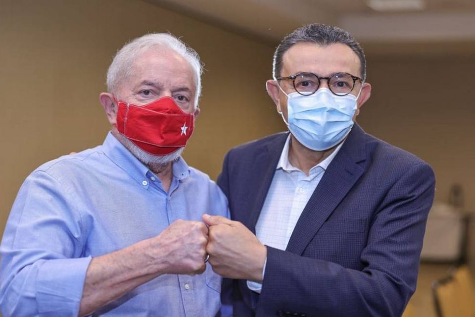 O ex-presidente Lula cumprimenta o presidente do PSB, Carlos Siqueira, durante uma reunião. Ambos usam máscara e encostam os punhos - Metrópoles