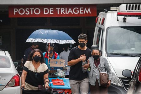 Pessoas doentes em hospital com placa escrito Posto de Triagem