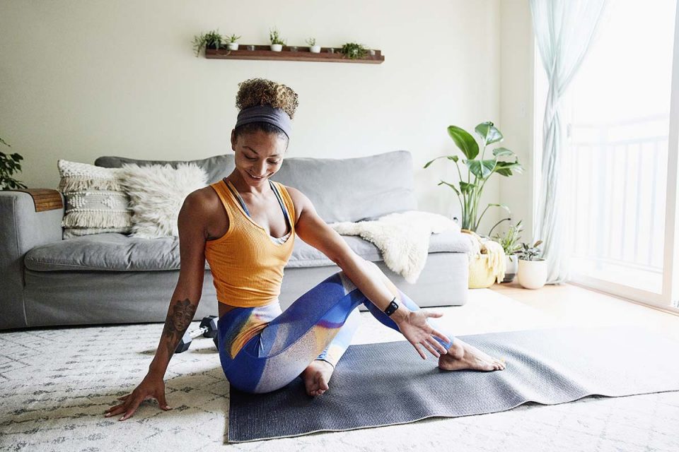 Mulher com roupa de malhar fazendo exercício em casa