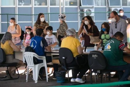 Pessoas de máscara em posto de saúde