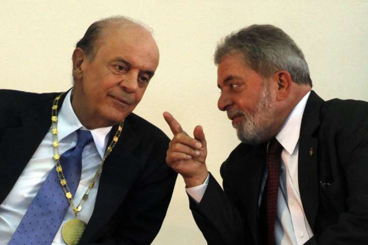 Na imagem, José Serra (PSDB) e Lula (PT), ainda presidente, conversam em meio a evento. Ambos usam terno.