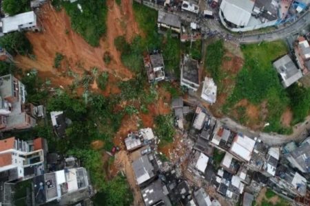 Na imagem colorida, lama está em cima de casas e arvores