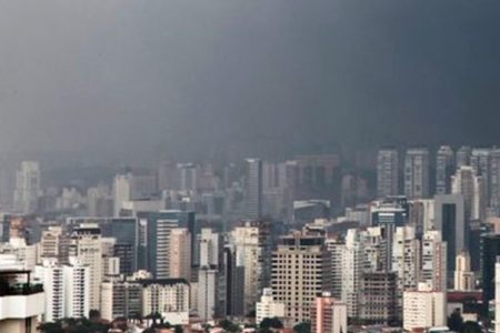 Na imagem colorida, prédios estão posicionados no centro. o céu está com neblina em dia de fortes temporais em São Paulo