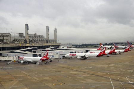 Imagem colorida mostra aviões parados no aeroporto do Galeão, no Rio de Janeiro; cinco aeronaves são brancas com detalhes em vermelho e três são brancas com detalhes em vermelho e azul - Metrópoles