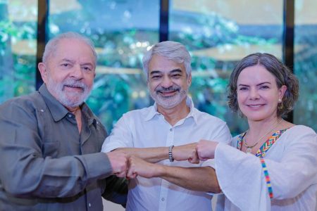 Na foto, estão de frente o ex-presidente Lula, o senador Humberto Costa e a deputada federal Gleisi Hoffman, todos do PT. Eles sorriem e encostam as mãos, frente a uma janela - Metrópoles