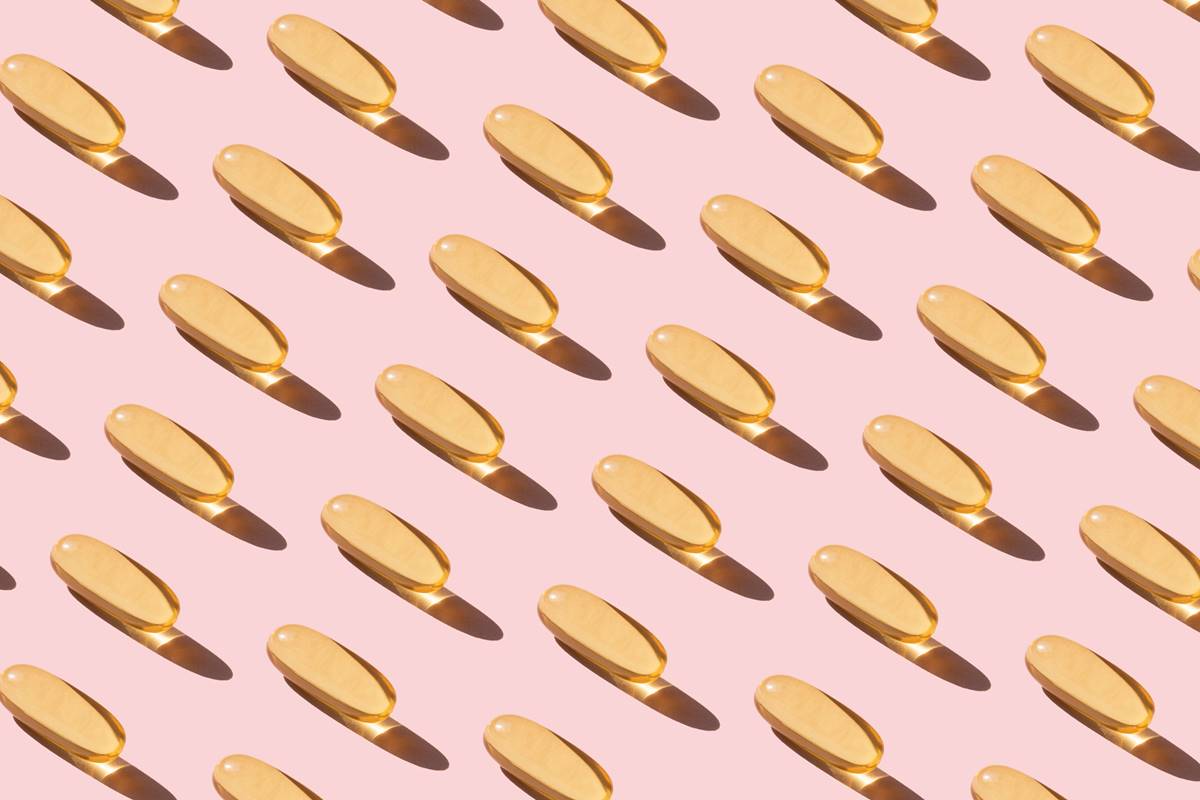 cápsulas de vitamina D em fundo rosa