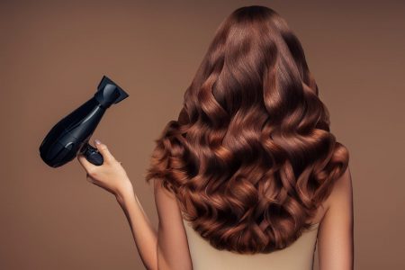 Mulher de costas e com cabelo ruivo segura secador