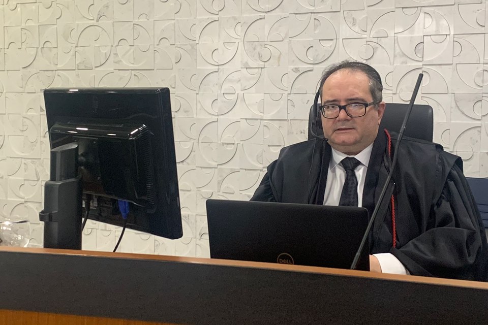 Homem de óculos, terno e gravata sentado em frente a computador