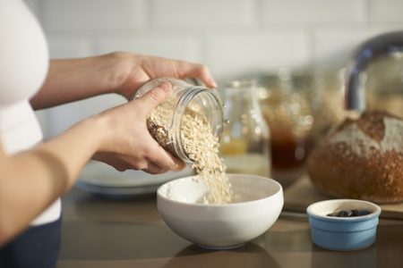 Uma pessoa está despejando aveia entro de uma tijela pequena com a cor clara - Metrópoles