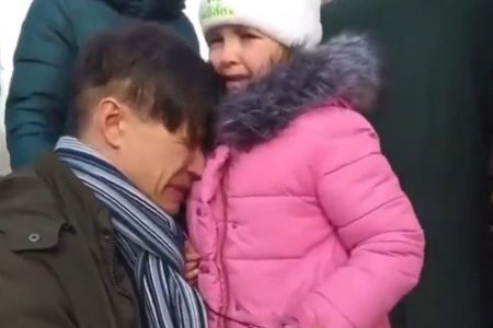 Em vídeo pai chora com filha pequena minutos antes de ter que se separar dela para mandar a menina a um lugar segura, enquanto ele se alista no exército ucraniano após invasão russa. A menina usa casaco rosa e o pai chora abaixado, com a cabeça encostada nela - Metrópoles