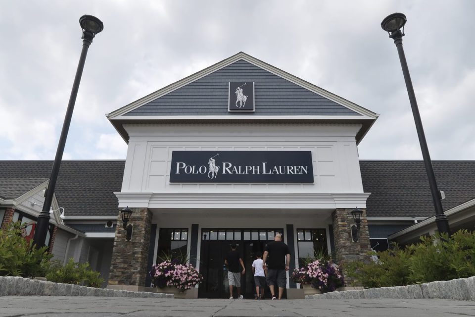 Fachada da loja da Ralph Lauren. O estabelecimento fica em um shopping ao céu aberto, provavelmente um outlet. É possível ver pessoas entrando no recinto.