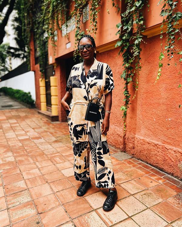 mulher negra usa macacão estampado e bolsa preta da balenciaga