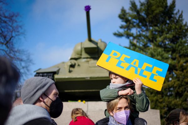 Participantes protestam contra a guerra na Ucrânia com uma placa com a inscrição "Paz" no memorial aos soldados soviéticos mortos na Segunda Guerra Mundial em frente a um tanque soviético T34