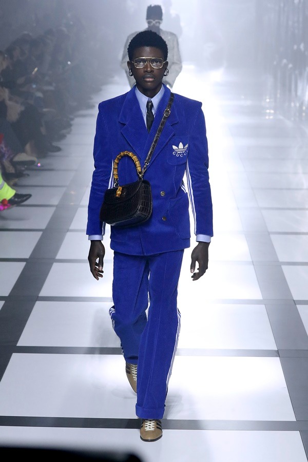 Na imagem com cor, modelo desfila com itens da parceria entre a Gucci e Adidas