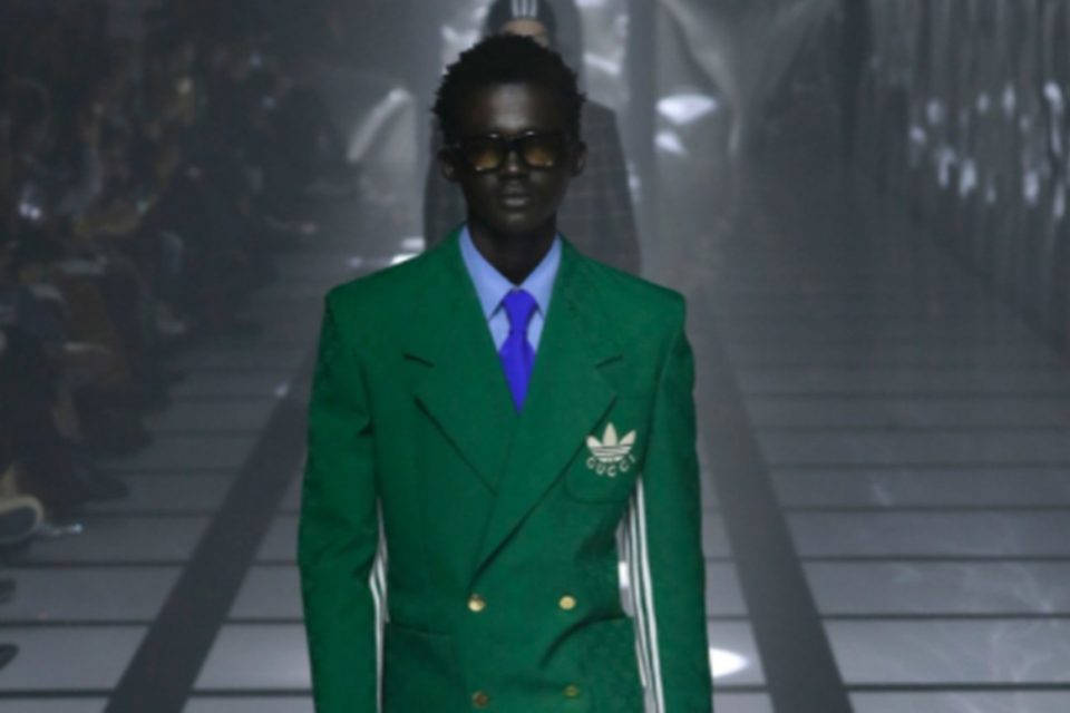 Na imagem com cor, modelo desfila com itens da parceria entre a Gucci e Adidas