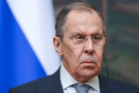 Ministro das Relações Exteriores da Rússia, Sergei Lavrov, fala de possível Terceira Guerra Mundial. Ele olha sério para frente com a bandeira russa atrás - Metrópoles