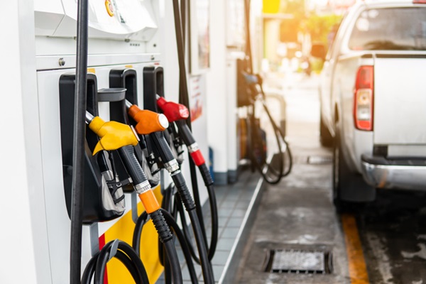 Fotografia de um posto de gasolina com bombas de gasolinae um carro na frente