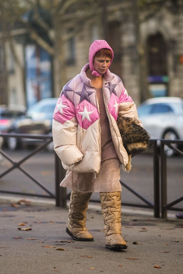 Na imagem com cor, mulher anda pela rua com uma balaclava na cabeça