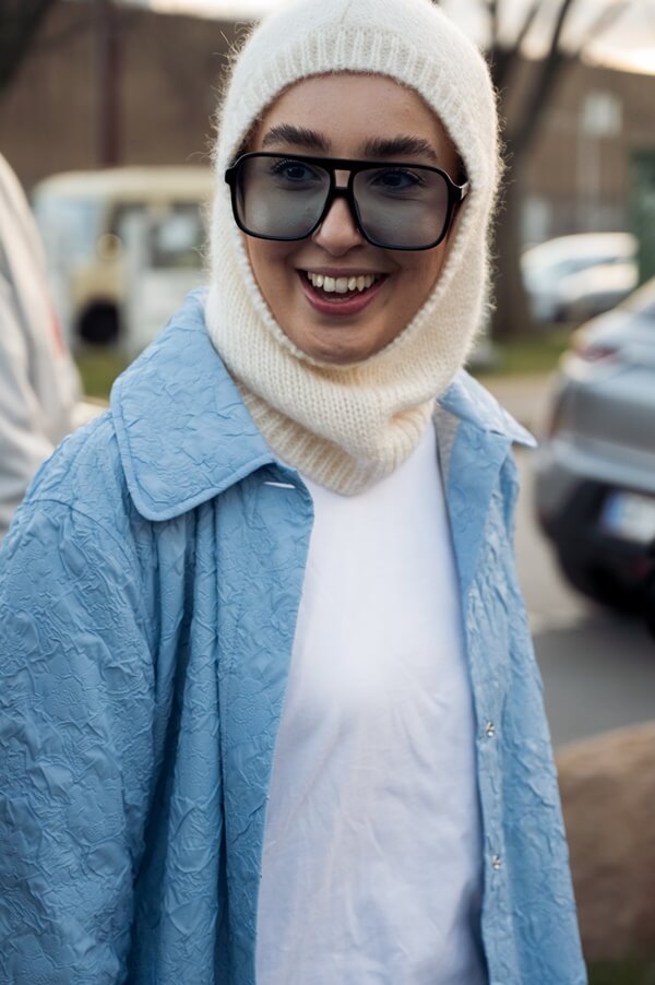 Na imagem com cor, mulher anda pela rua com uma balaclava na cabeça