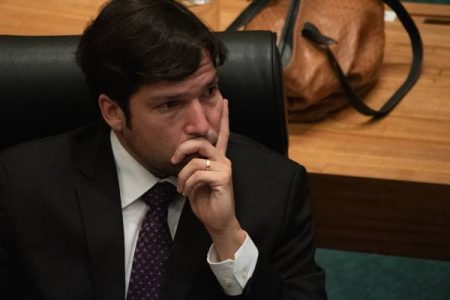 Homem segura queixo com a mão esquerda