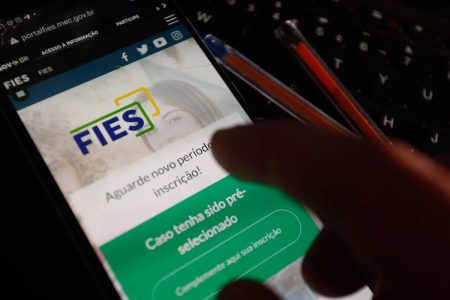 pessoa segura um celular em que acessa o aplicativo do FIES