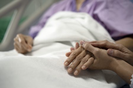cuidadora de mãos dadas com idosa hospital