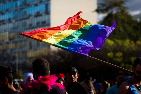 Pessoas manifestam em rua com bandeira LGBT