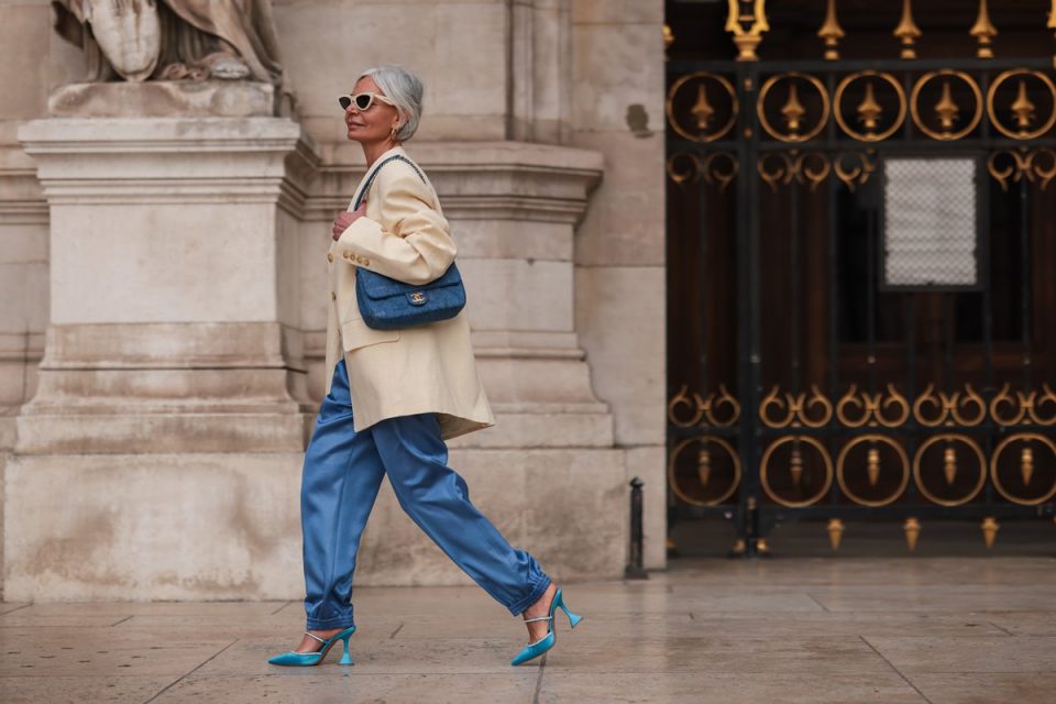Look com macacão azul acetinado, scarpin azul e bolsa azul, além de blazer branco, no street style
