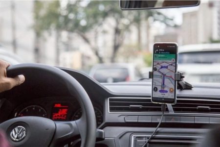 painel de um carro homem dirigindo e celular aberto nos mapas