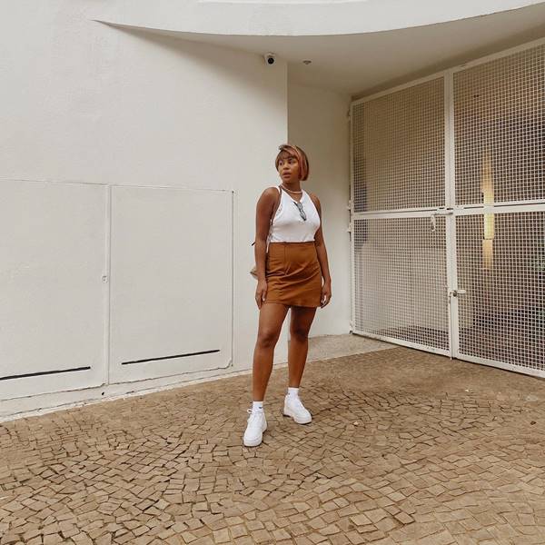 Mulher usa saia caramelo e blusa branca