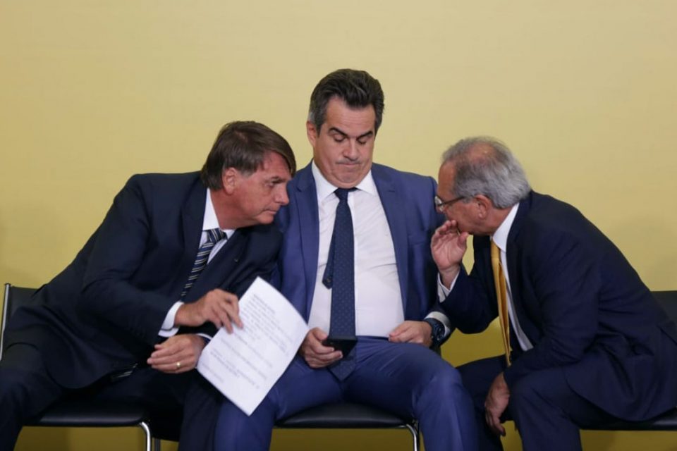 O presidente Bolsonaro conversa com o ministro da Economia Paulo Guedes. Entre os dois, o ministro da Casa Civil, Ciro Nogueira. Eles estão sentados em lançamento do Programa Renda e Oportunidade, no Planalto. - Metrópoles