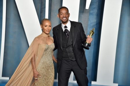 Jada Pinkett Smith e seu marido, o ator Will Smith em premiação do Oscar. Ela tem a cabeça raspada, de vestido bege, e ele usa terno, sorrindo, e segura a estatueta do prêmio - Metrópoles