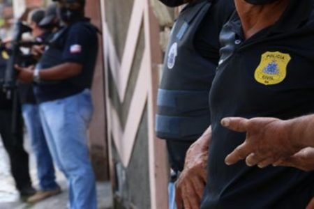 Dois policiais pardos com colete a prova de bala.