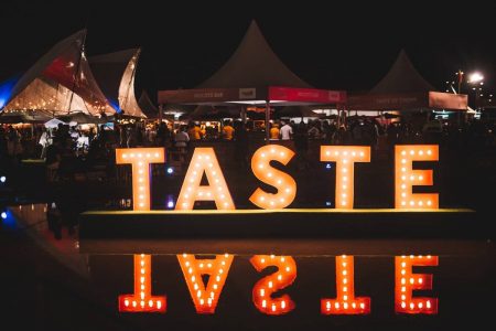 foto de feira com letreiro luminoso escrito taste