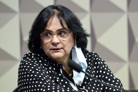 Fotografia colorida de mulher com máscara pendurada na orelha