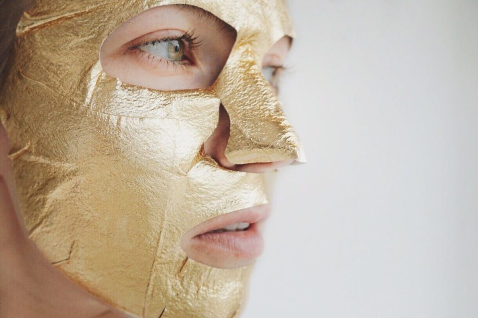 Rosto de mulher com máscara facial dourada