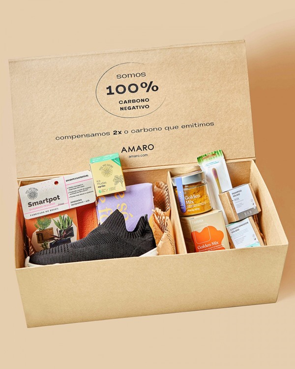 Caixa de papelão da marca Amaro com produtos. É possível ver itens como tênis, escova de dentes, produtos de beleza e até alimentícios