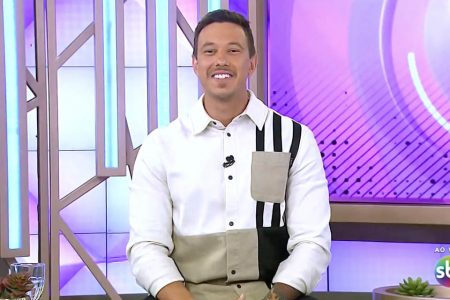 Gabriel Cartolano. Ele é um homem branco, de cabelo preto, está sentado e sorrindo em um estúdio de tv - Metrópoles