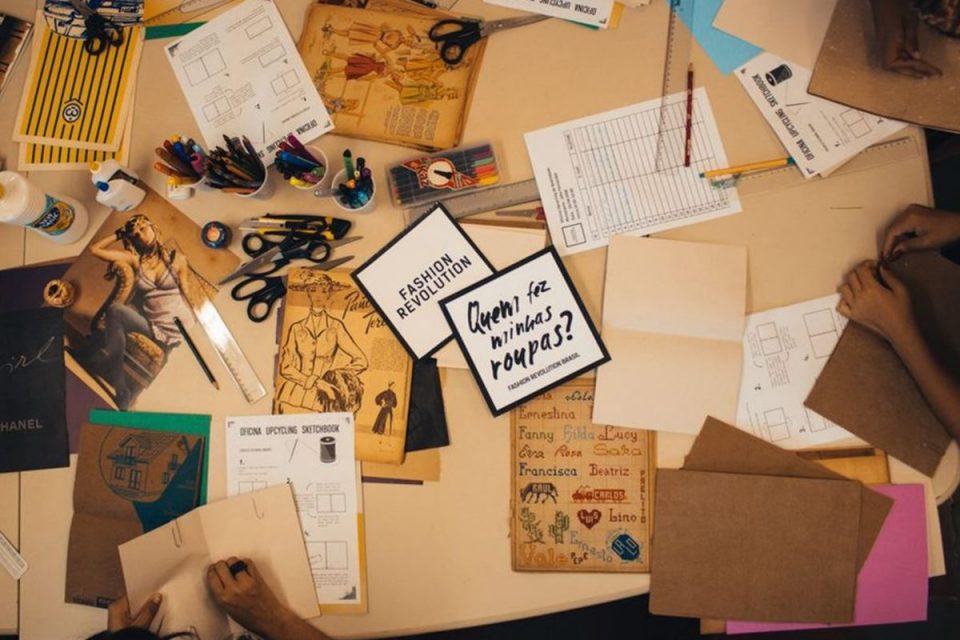 Mesa de estudos e colagens com papéis, tesoura, canetas e tinta