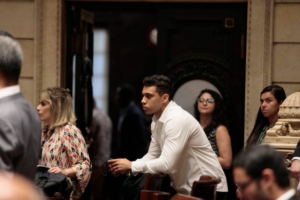 Fotografia colorida mostra o ex-vereador Gabriel Monteiro em plenário, cercado por outras pessoas. / Metrópoles