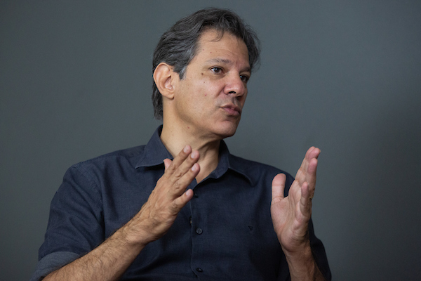 O pré-candidato ao governo de São Paulo, Fernando Haddad (PT), concede entrevista ao Metrópoles. Ele gesticula, sentado sob fundo cinza - Metrópoles