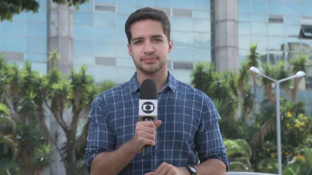 Gabriel Luiz, repórter da TV Globo, segurando microfone