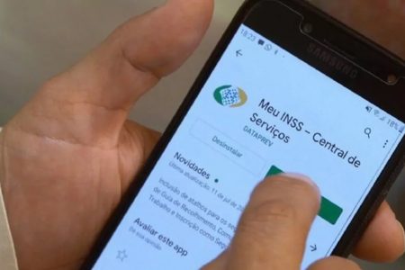 pessoa usa o celular para consultar informações no aplicativo do INSS