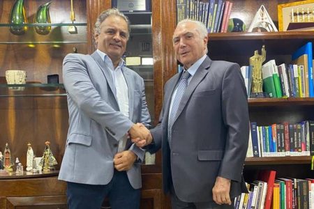 O deputado federal Aécio Neves cumprimenta o ex-presidente Michel Temer num escritório cheio de livros nas prateleiras - Metrópoles
