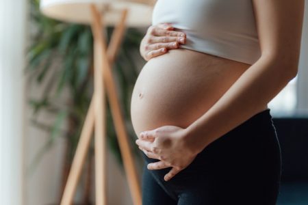 Mulher grávida com as mãos na barriga - Metrópoles